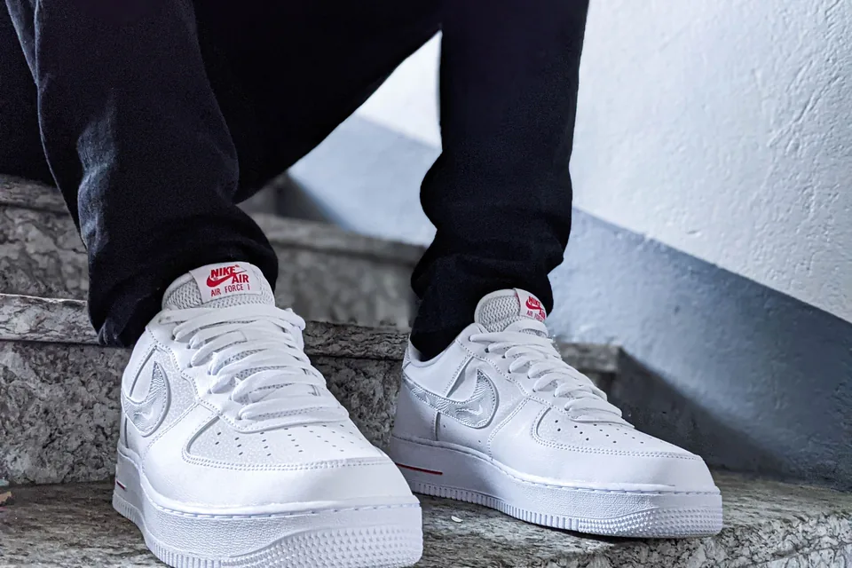 Nike Air Force 1 Low blanche et noire au design épuré, posée sur fond neutre, panneaux graphiques visibles.